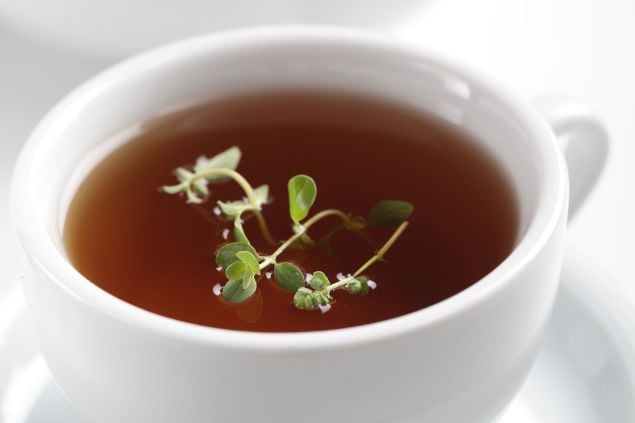 Imagem de um chá com folhas de manjerona flutuando sobre o chá