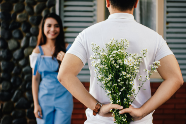Homem surpreendendo uma mulher com um buquê de flores brancas