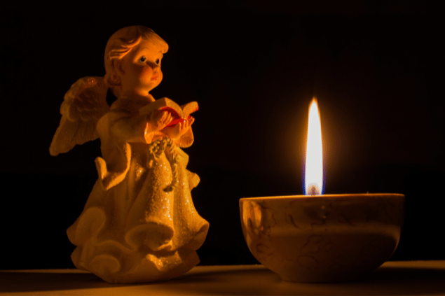 Estátua de anjo em frente a uma vela acesa