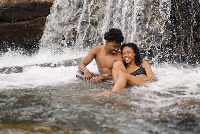 Homem e mulher negros numa cachoeira.