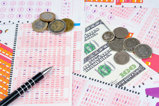 Várias cartelas de jogos de lotérica com moedas, notas e canetas em cima