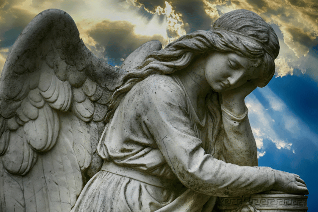 Estátua de anjo representando Sitael em um céu azul com nuvens iluminadas pelo o sol.