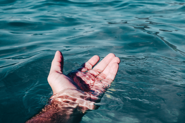 Pessoa com a mão na água do mar