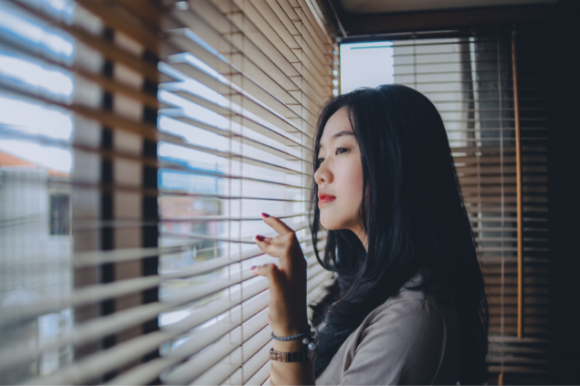 Mulher asiática observando pela janela