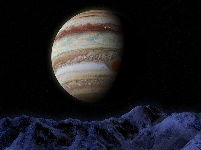 Imagem do planeta Júpiter visto sobre montanhas.