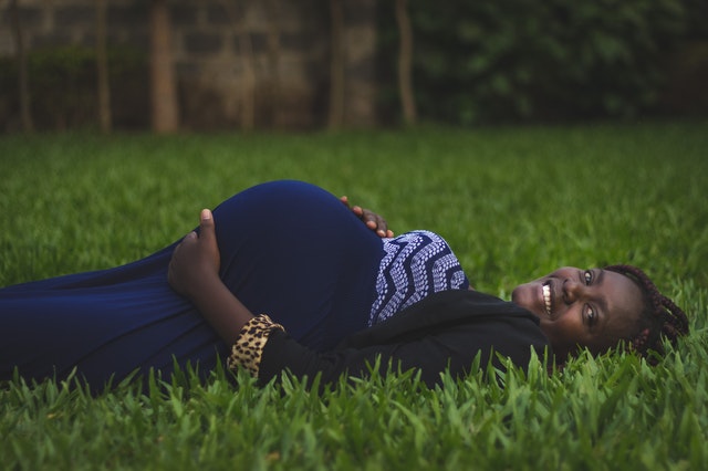 Mulher negra grávida deitada.